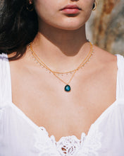 Load image into Gallery viewer, Close-up of a person wearing a gold necklace with a green pendant, against a blurred natural background.
